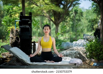 Asian yoga girl doing flexibility yoga exercise on mat. Peaceful girl standing in forward bend exercise, head to knees Uttanasana pose, fitness woman doing gymnastic physical training exercise.