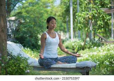 Asian yoga girl doing flexibility yoga exercise on mat. Peaceful girl standing in forward bend exercise, head to knees Uttanasana pose, fitness woman doing gymnastic physical training exercise.