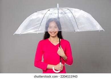 Asian Young Adult 20s Woman With Long Black Straight Hair Wear Pink Dress. Female Hold Transparent Umbrella, Feeling Emotion Fashion Happy Smile, Gray Background Isolated Copy Space