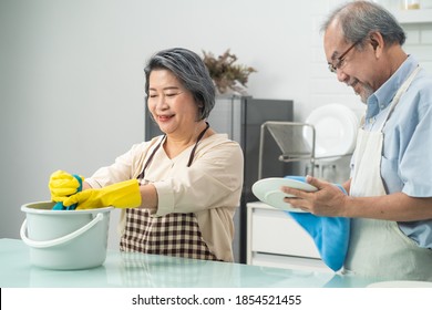 Asian Young Aged Housewife Twisting Wet Rag To Clean The Kitchen Counter. The Old Woman Wiping The Cloth On Table After Cooking The Food For Hygiene And Healthy At Home.