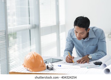 Asian Young Architect Working On Blueprint In The Office