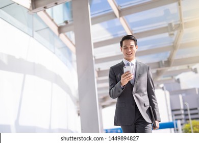 Asian Young Attractive Business Man Using Smartphone At Front Building.