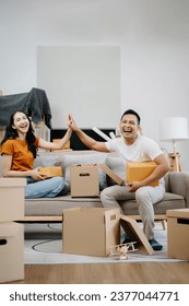 Asian young attractive couple man and woman use tablet and smartphone online shopping furniture decorate house with carton package move in new house. Young married asian moving home. in morning
