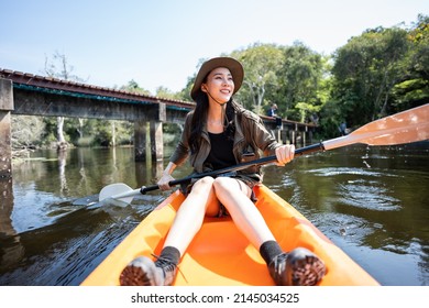 Asian young attractive tourist woman rowing kayak alone in forest lake. Backpacker traveler girl travelling and kayaking on canoe in beautiful mangrove forest enjoy spend time on holiday vacation trip