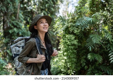 Asian young beautiful female backpacker traveling alone in forest wild. Attractive girl traveler look around and explore while walk in nature wood with happiness and fun during holiday vacation trip.