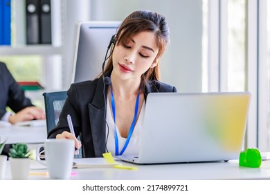Asian young beautiful female businesswoman operator wearing headset with microphone working at helpdesk service laptop computer helping consulting with customers call center - Shutterstock ID 2174899721