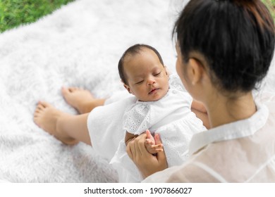 Asian Young Beautiful Mother Holding Her Newborn Is Sleeping And Feel With Love And Touching Gently Then Sitting On Green Grass In The Park