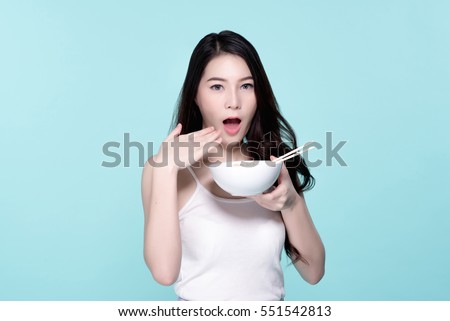 Asian young beautiful woman eating hot and spicy instant noodle,  beauty face natural makeup, isolated over blue background.