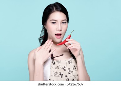 Asian Young Beautiful Woman Holding Red And Green Chili Pepper, Hot And Spicy Food, Natural Makeup, Beauty Face, Isolated Over Blue Background.