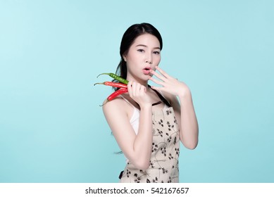 Asian Young Beautiful Woman Holding Red And Green Chili Pepper, Hot And Spicy Food, Natural Makeup, Beauty Face, Isolated Over Blue Background.