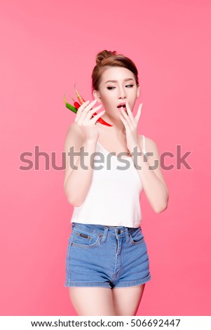 Asian young beautiful woman holding red chili pepper, hot and spicy food, natural makeup, beauty face, isolated over pink background.
