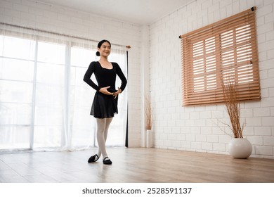 Asian young beautiful woman practice dancing ballet rehearsing at home. Attractive young girl ballet dancer spinning and jumping in a tutu and pointe shoes, doing stretching dance with yoga elements. - Powered by Shutterstock