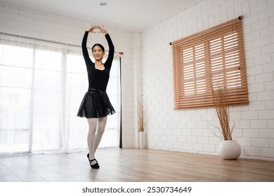 Asian young beautiful woman practice dancing ballet rehearsing at home. Attractive young girl ballet dancer spinning and jumping in a tutu and pointe shoes, doing stretching dance with yoga elements. - Powered by Shutterstock