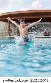 Asian Young Boy Having A Good Time In Swimming Pool, He Jumping And Playing A Water In Summer.