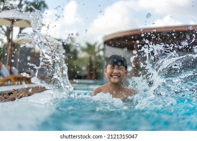 Asian Young Boy Having A Good Time In Swimming Pool, He Jumping And Playing A Water In Summer.