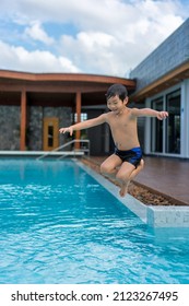 Asian Young Boy Having A Good Time In Swimming Pool, He Jumping And Playing A Water In Summer.