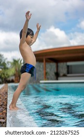 Asian Young Boy Having A Good Time In Swimming Pool, He Jumping And Playing A Water In Summer.