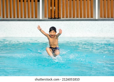 Asian Young Boy Having A Good Time In Swimming Pool, He Jumping And Playing A Water In Summer.