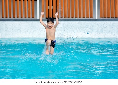 Asian Young Boy Having A Good Time In Swimming Pool, He Jumping And Playing A Water In Summer.