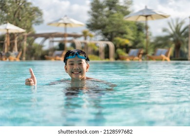 Asian Young Boy Having A Good Time In Swimming Pool, He Jumping And Playing A Water In Summer.