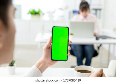 asian young businessman look to green screen smart phone in the office - Powered by Shutterstock