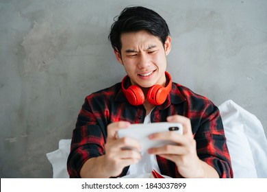 Asian Young Businessman Playing Mobile Game On Smartphone With Serious Looking.