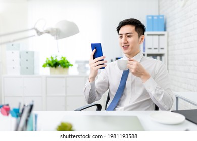 asian young businessman is reading news by smartphone and drinking coffee in the office - Powered by Shutterstock