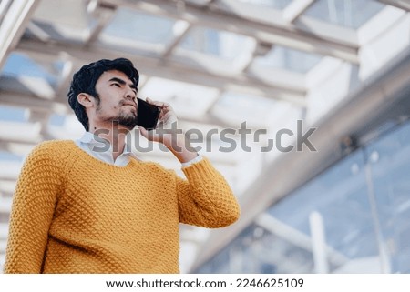 Asian young businessman using mobile phone outside an office building.