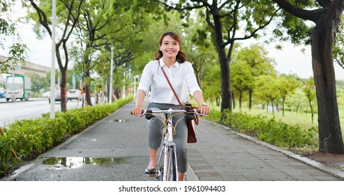 Asian young businesswoman commute by bicycle through the city happily