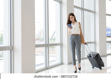 Asian Young Businesswoman Use Smart Phone With Suitcase On Her Business Trip