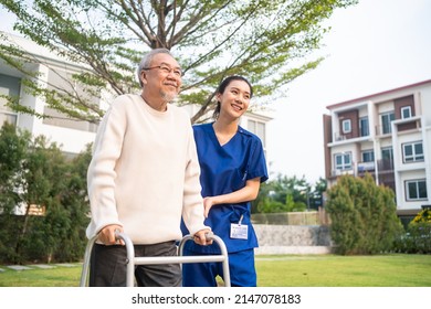 Asian young caregiver nurse support senior older male walking outdoors. Specialist girl doctor help and take care of elderly mature man patient doing physical therapy in public park at nursing home. - Powered by Shutterstock