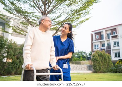 Asian young caregiver nurse support senior older male walking outdoors. Specialist girl doctor help and take care of elderly mature man patient doing physical therapy in public park at nursing home. - Powered by Shutterstock