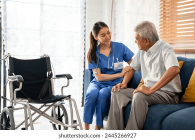 Asian young caregiver take care senior man on wheelchair in house. Attractive nurse doctor support elderly older mature male patient sitting on sofa at nursing home care. Medical insurance concept. - Powered by Shutterstock