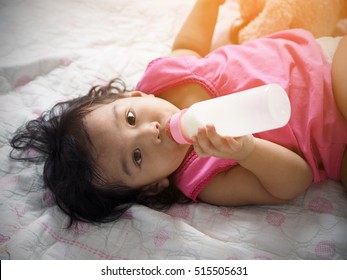 Asian young children are drinking milk by self.