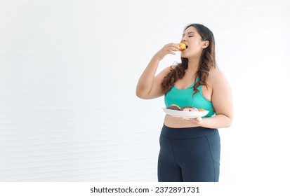 Asian young chubby fat unhealthy oversized overweight plus size female sportswoman in sportswear sports bra legging standing  holding eating mixed flavor sweet sugar dessert donuts from plate. - Shutterstock ID 2372891731