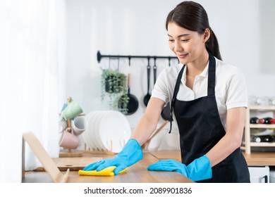 Asian young cleaning service woman worker clean kitchen table at home. Beautiful young girl housekeeper cleaner feel happy and wiping messy dirty cooking counter for housekeeping housework or chores. - Shutterstock ID 2089901836