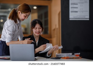 Asian Young Colleague Business Presents And Explains And Using Laptop Computer In An Office. Teamwork, Coworker Cooperation, Financial Marketing Team, Or Corporate Business Employee Concept.