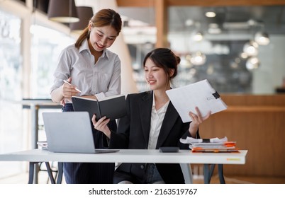 Asian Young Colleague Business Presents And Explains And Using Laptop Computer In An Office. Teamwork, Coworker Cooperation, Financial Marketing Team, Or Corporate Business Employee Concept.