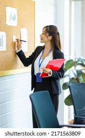 Asian Young Confident Professional Female Businesswoman Employee Staff In Formal Suit Holding Clipboard And Pen Pointing Presenting Sales Target Graph Chart Diagram Paperwork On Board In Meeting Room.