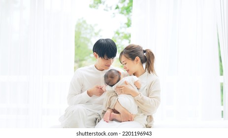 Asian young couple and a baby in house. Child rearing. Newborn.