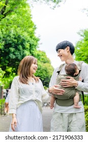 Asian Young Couple  And A Baby Walking In Green Park. Child Rearing. Newborn.