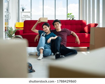 Asian Young Couple Boy And Girl Relaxed Sitting After Break From Carrying And Moving Cardboard And Parcel Come Into New Home Together And Then She Smiling And Holding Relocation Gift From Neighbor