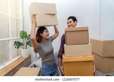 Asian Young Couple Carrying Big Cardboard Box For Move In New Home, Moving And House Hunting Concept, Selective Focus