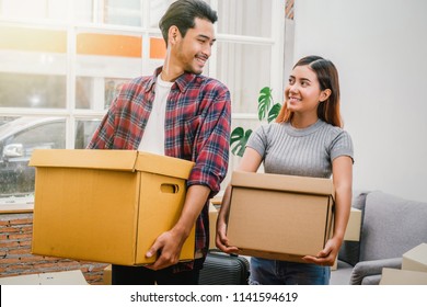 Asian Young Couple Carrying Big Cardboard Box For Moving In New House, Moving And House Hunting Concept