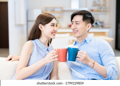 Asian Young Couple Chatting And Drinking Beverage At Home