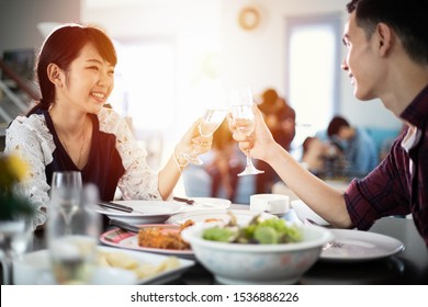 Asian Young Couple Enjoying A Romantic Dinner  Evening Drinks While Sitting At The Dinning Table On The Kitchen Together