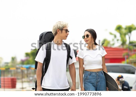 Asian young couple or friends man and woman playing surfskate or skate board in urban city outdoor. Extream sports 