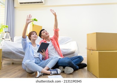 asian young couple have interior design discussion for their new home and digital tablet    they sitting wooden floor   having dreams in house