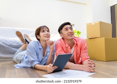 asian young couple have interior design discussion for their new home and digital tablet    they lying wooden floor   having dreams in house