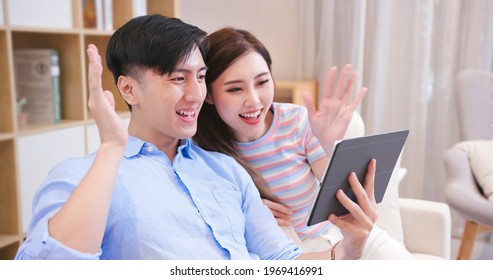 Asian Young Couple Have Video Chat With Digital Tablet At Home Happily